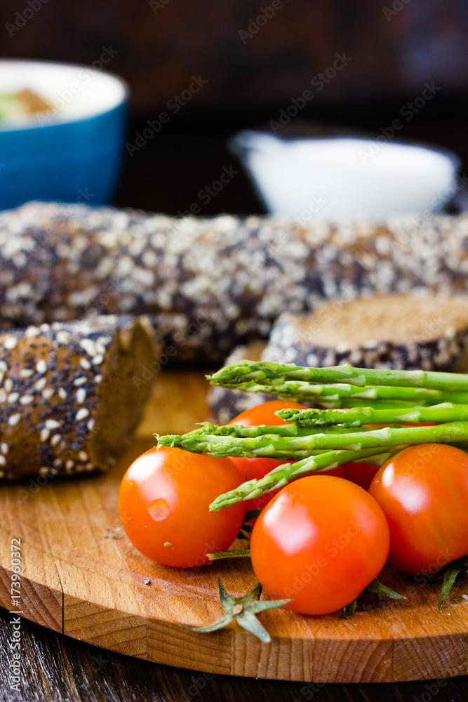 Fresh and ripe asparagus and cherry tomatoes with bread on wooden board. Fresh and ripe asparagus and cherry tomatoes with bread on wooden board.