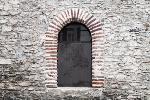 Arched window in old gray stone wall