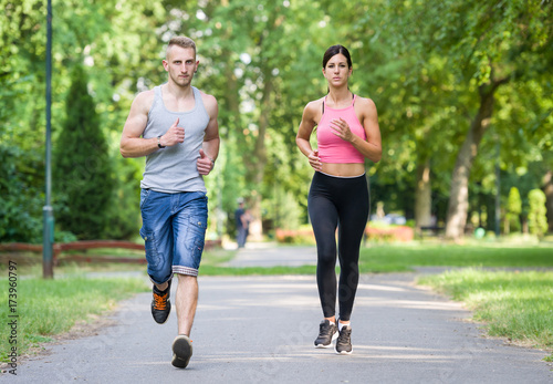 sport woman and man running together in a park in summer