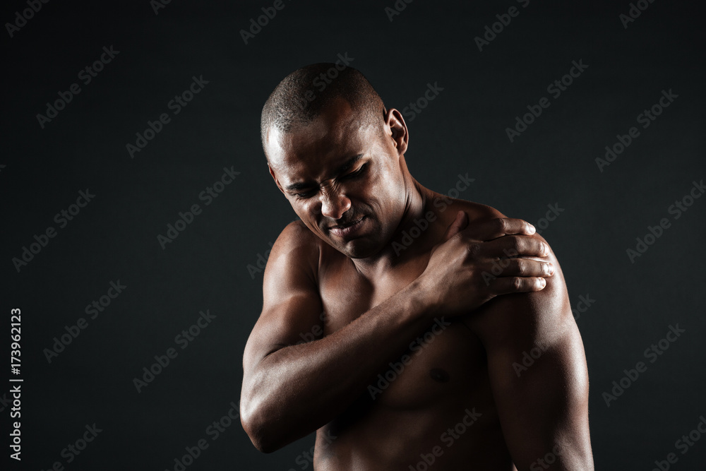Closeup photo of young shirtless afro american man with shoulder pain