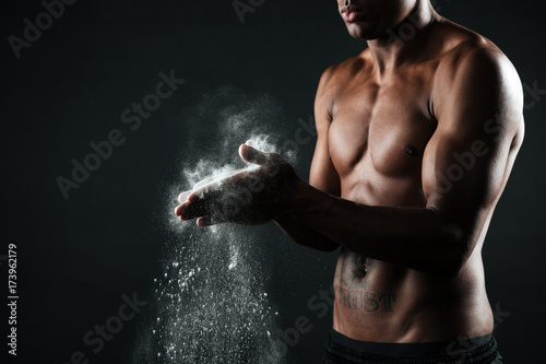 Fototapeta Naklejka Na Ścianę i Meble -  Cropped image of handsome afro american sports man rubbing hands with chalk