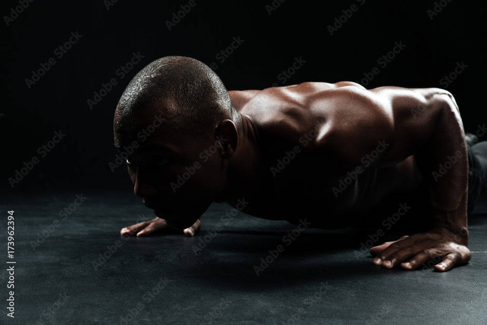 Close-up portrait of afro american sports man, with beautiful muscular body doing pushup exercise on floor