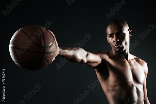 Young serious basketball player holding ball with one hand © Drobot Dean