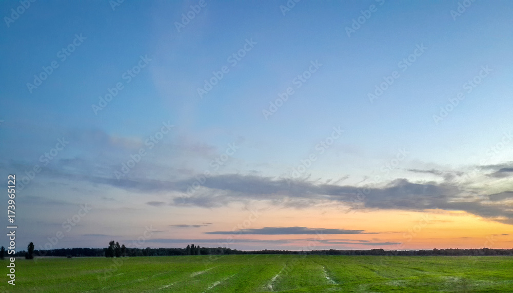 Spectacular landscape with green field and turquoise blue sunset sky