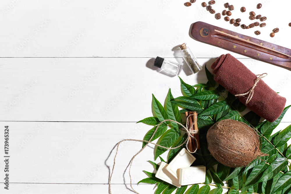 Natural handmade soaps with coffee beans, brown towel, coconut and green leaves on white wooden background Natural handmade soaps with coffee beans, brown towel, coconut and green leaves on white wooden background