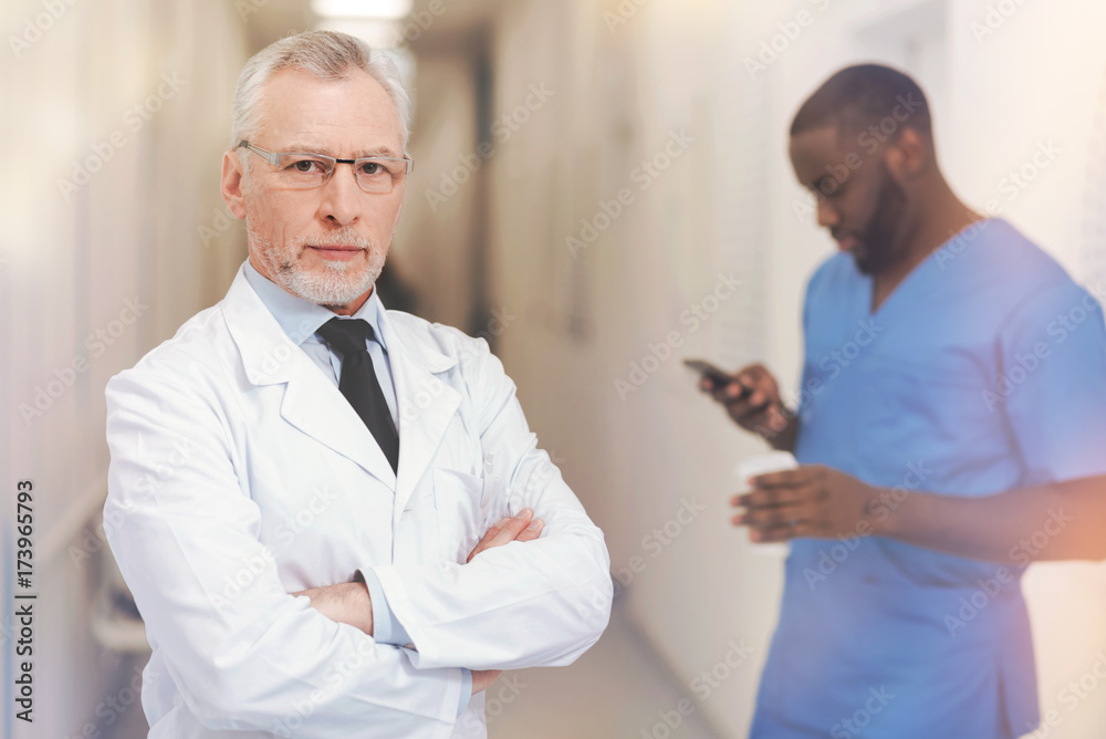 Serious grey-haired man keeping arms crossed on chest Serious grey-haired man keeping arms crossed on chest