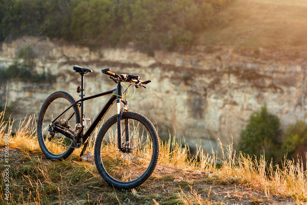 Mountain bike stands alone outdoor against autumn sunset landscape