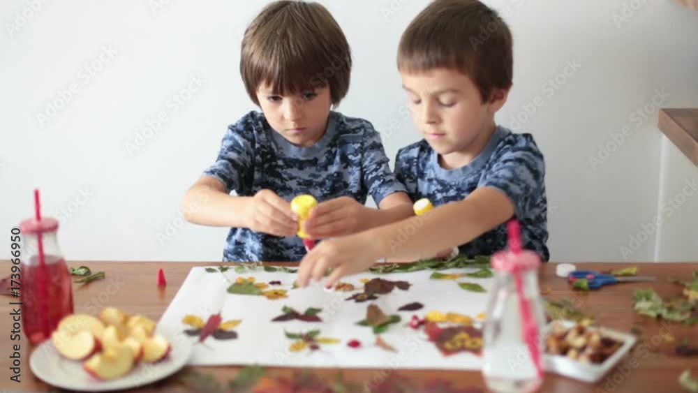 Sweet children, boys, applying leaves using glue while doing arts and crafts in school, autumn time Sweet children, boys, applying leaves using glue while doing arts and crafts in school, autumn time