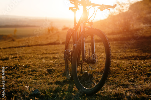 Mountain bike stands alone outdoor against autumn sunset landscape