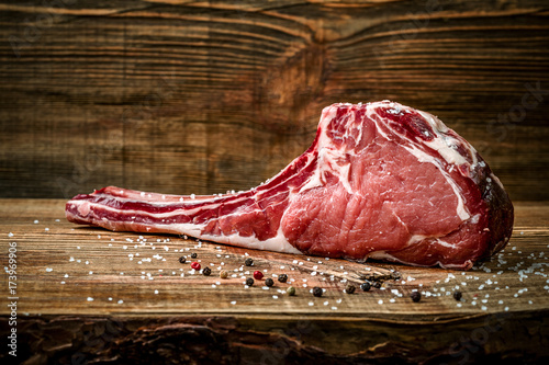 Dry aged raw tomahawk beef steak with ingredients for grilling