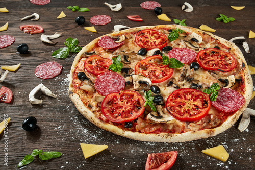 Closeup of pizza with salami, tomatoes and olives photo