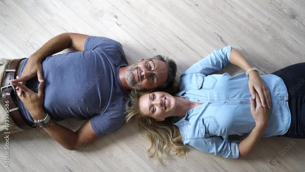 Upper view of couple laying on wooden floor at home