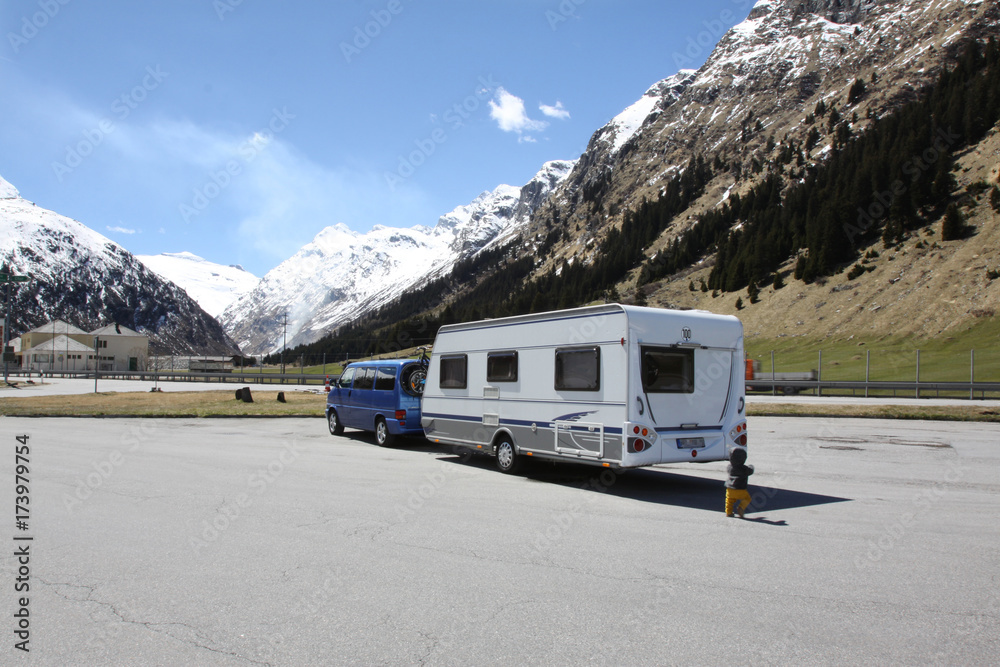 Ein Bus mit einem Wohnanhänger steht auf einem Parkplatz am Alpenpass San Bernardino in der Schweiz Ein Bus mit einem Wohnanhänger steht auf einem Parkplatz am Alpenpass San Bernardino in der Schweiz