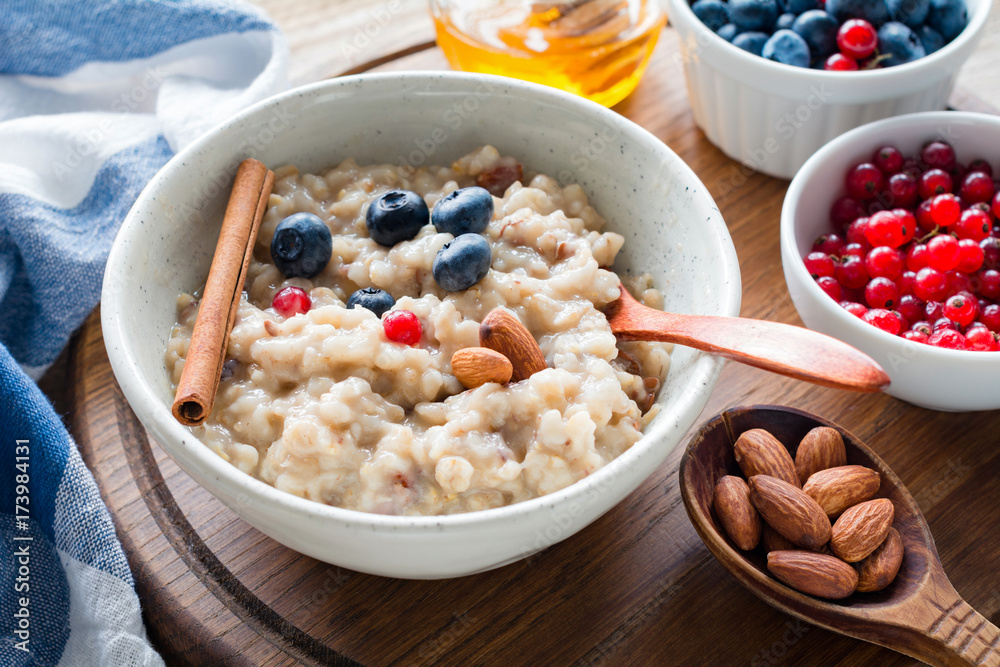 Oatmeal porridge with blueberries, almonds and currants in bowl. Healthy breakfast, dieting, balanced meal concept