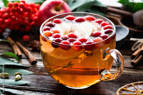 Herbal tea with cranberries, apple, giner, lemon, cinnamon and thyme in a glass. Warming tea, healthy fruit infused tea photo