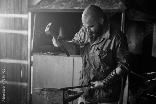 Blacksmith working in the forge. Manufacture of parts and weapons from molten metal, using the hammer and anvil.