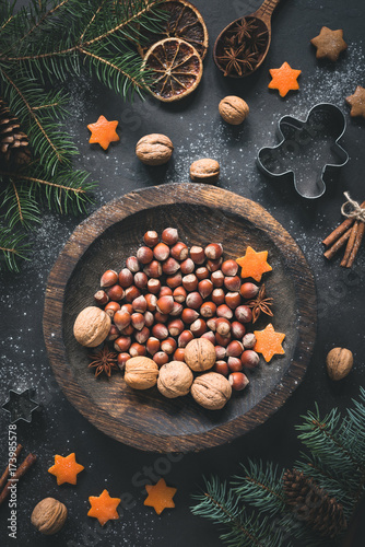 Christmas Winter decorations, walnuts, hazelnuts, Christmas tree branch, spices, cookie cutters and orange stars still life. Top view, toned image