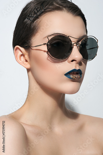 seductive woman in sunglasses posing against white background