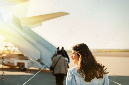 Young woman passager walking from the airport terminal to the airplane for departure.