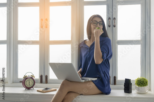 pretty woman relaxing with laptop and enjoy eating green apple beside window