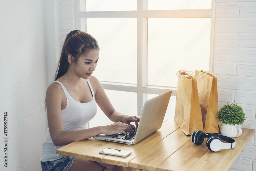 Obraz premium The girl is sitting happily shopping online by the window.