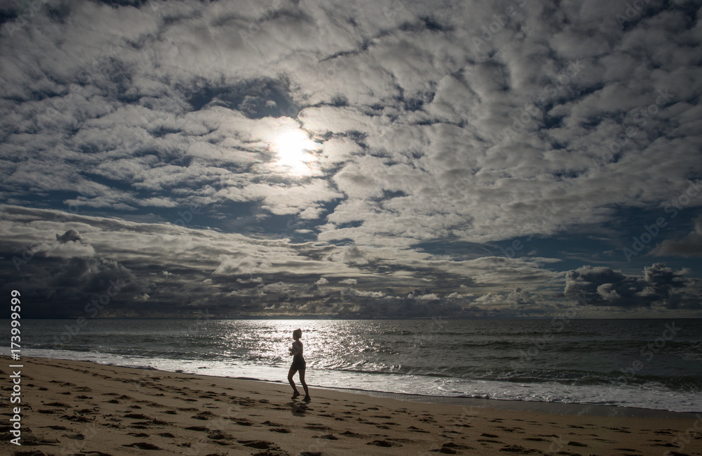 femme qui fait un jogging sur la plage au coucher du soleil