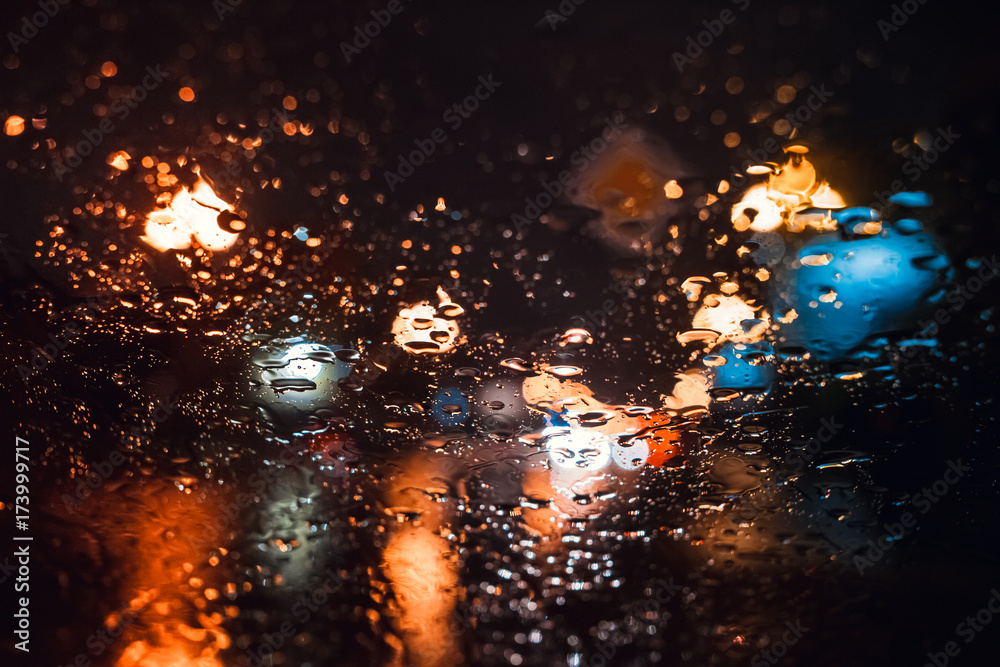 Magnificent city landscape in the side through the wet windshield of the car in the rain. Beautiful background