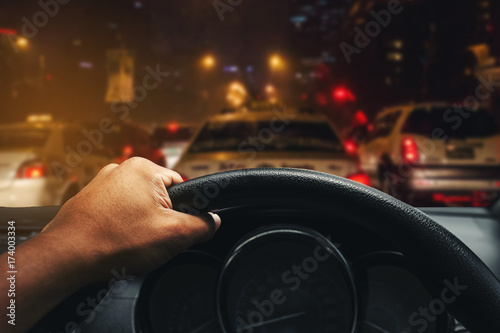 View on the dashboard of the truck driving.The driver is holding the steering wheel. Traffic jam at night is in front of the car.