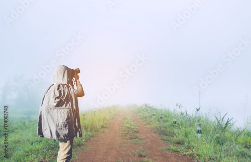 Asian male photographer in coat shooting photos while standing in Forest with space area for your text. © Khritthithat