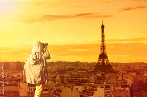 Asian male photographer in coat shooting photos while standing near Eiffel tower, Paris. France with copy space area for your text.