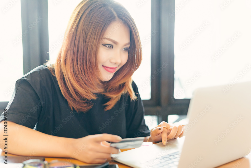 Asian stylish glasses woman designer wear black dress and red lips shopping with credit card on internet in selective focus.. Asian stylish glasses woman designer wear black dress and red lips shopping with credit card on internet in selective focus..