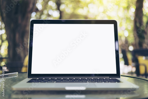 Mockup image of laptop with blank white screen on glass table at outdoor with green nature background photo