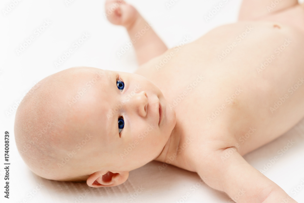 caucasian infant baby with beautiful blue eyes is lying on white surfase caucasian infant baby with beautiful blue eyes is lying on white surfase