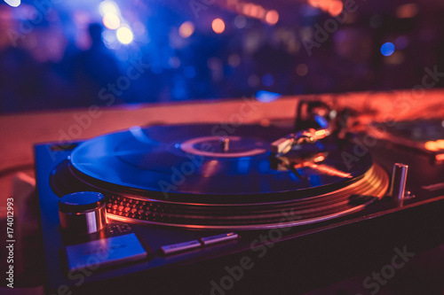 Vinyl record on the turntable in the music club in the light of blue and red light