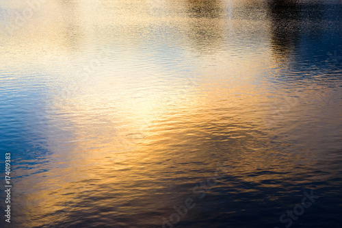 Reflection of golden sunset sky on the water surface.