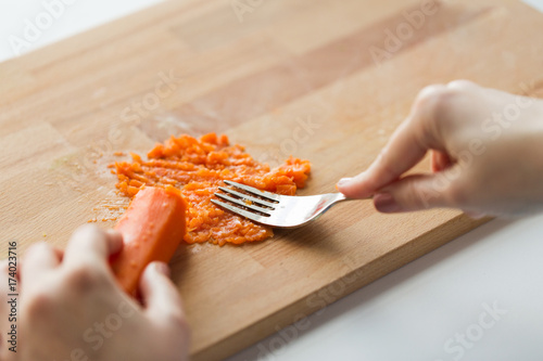 hand with fork making mashed carrot on board photo