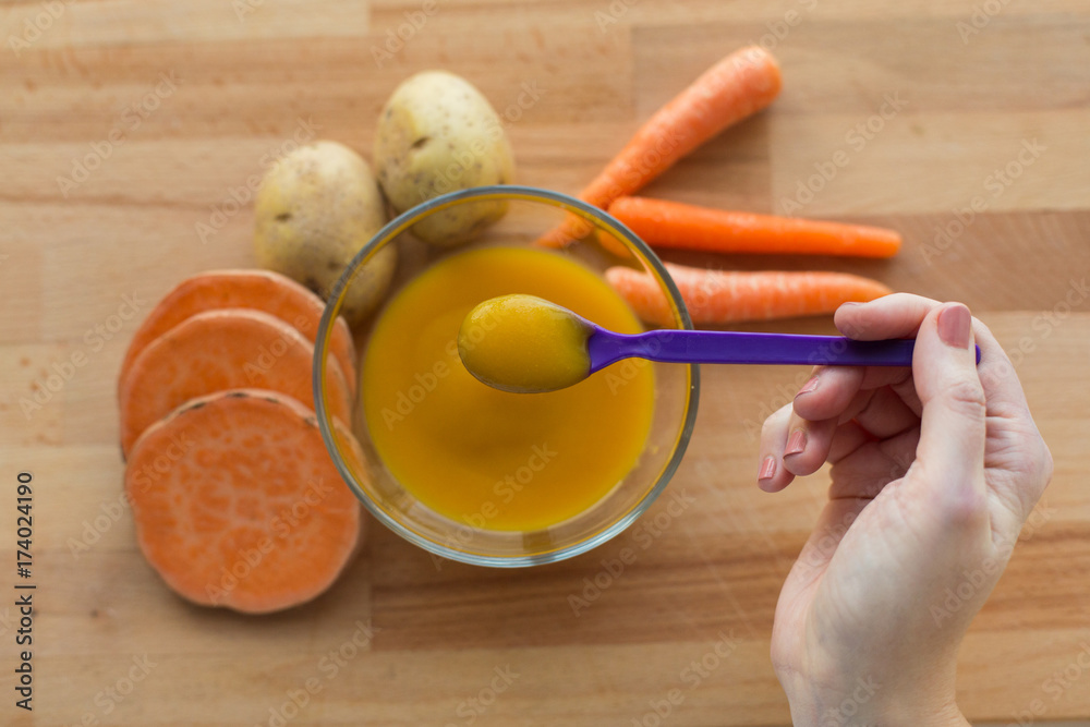 hand with vegetable puree or baby food in spoon hand with vegetable puree or baby food in spoon