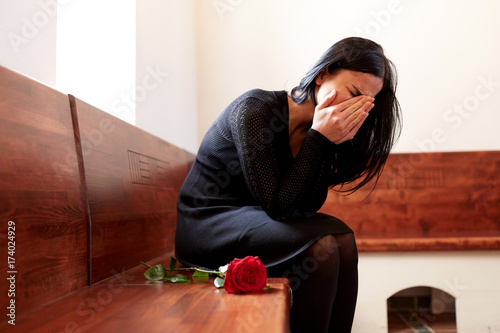 crying woman with red rose at funeral in church