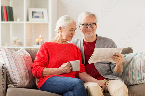 happy senior couple reading newspaper at christmas