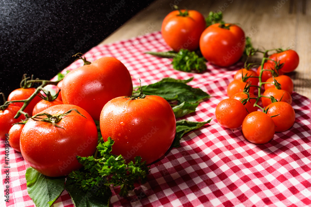 Many tomatoes are placed on a plaid tablecloth. Many tomatoes are placed on a plaid tablecloth.
