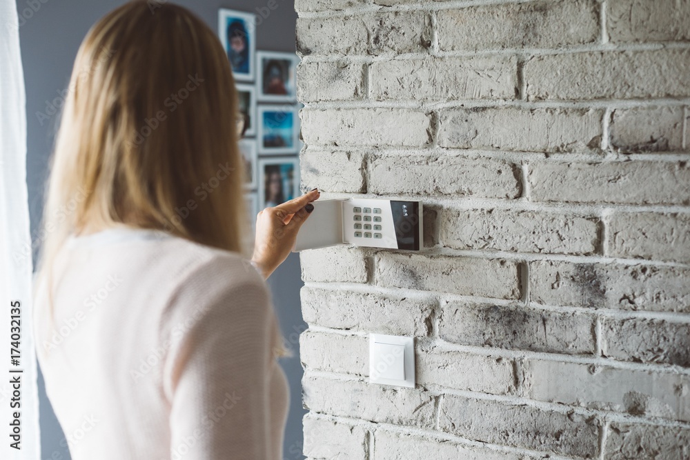 Woman entering pin on home alarm