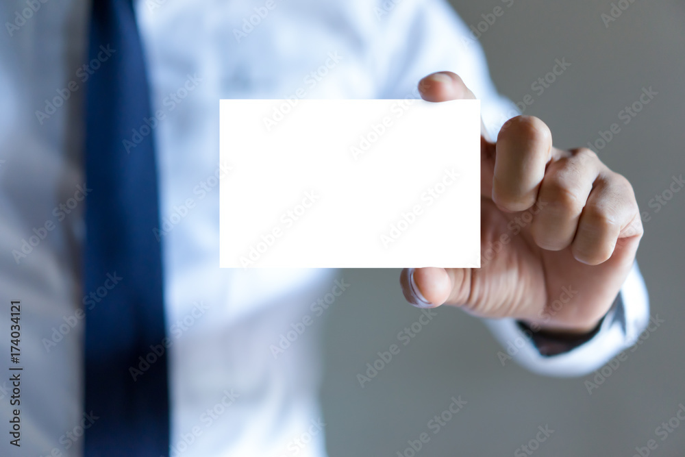 Man's hand showing business card - closeup shot on grey background Man's hand showing business card - closeup shot on grey background