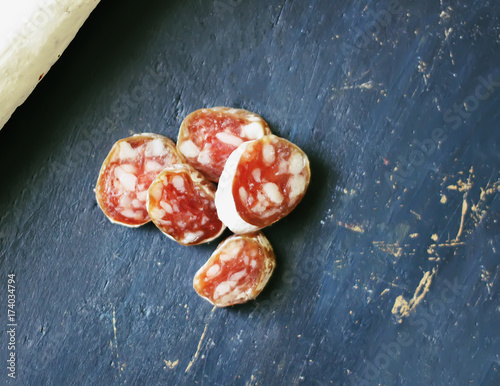 Dry cured sausage with spices on dark background photo