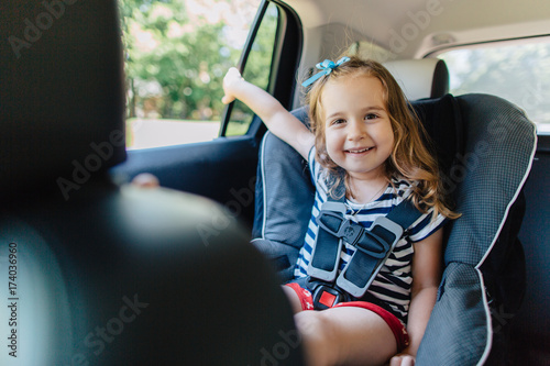 Cute young girl having fun in a car seat photo