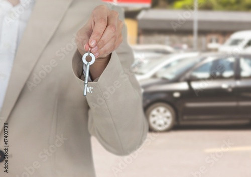 Hand Holding key in front of cars