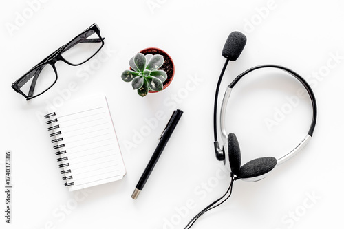 Call center manager's workplace. Headphones and notebook on white background top view