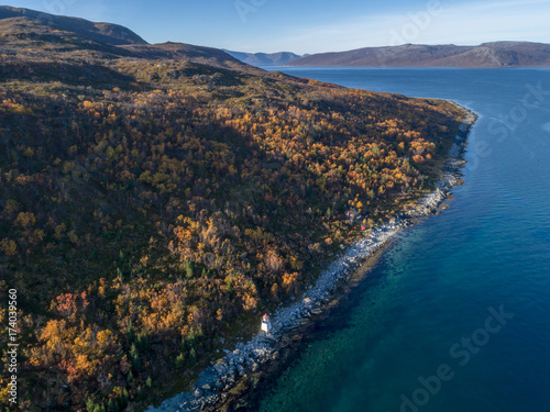 Aerial drone view of beautiful coastline with a lighthouse during autumn.