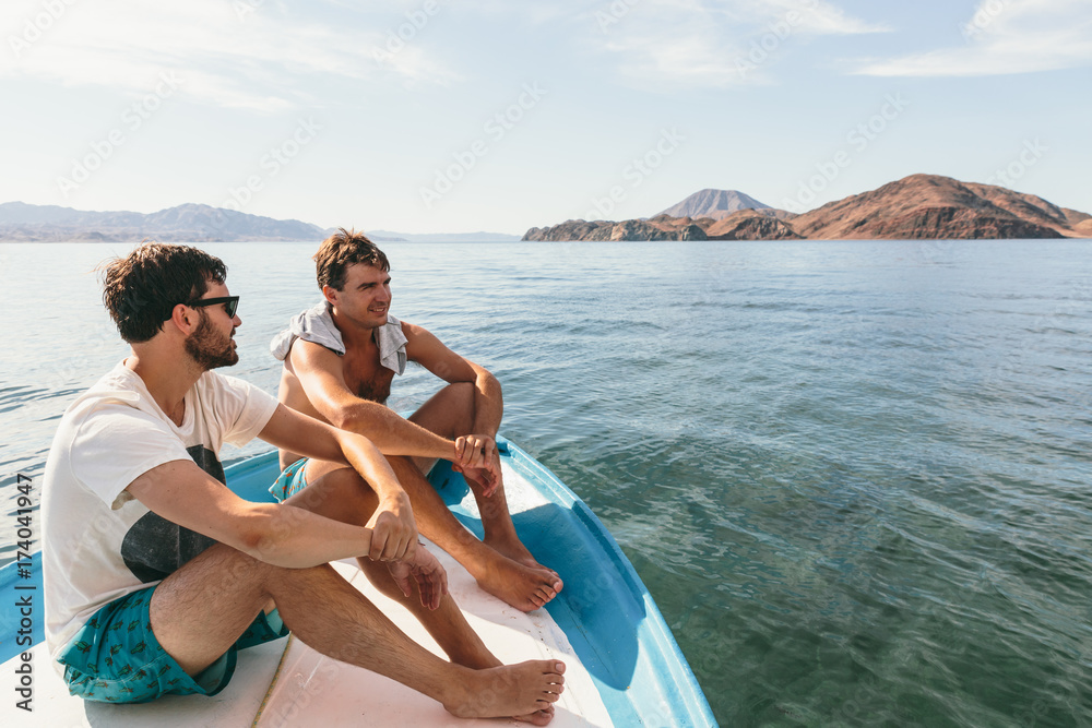 Two young men on a boat and view of sea and mountains while adventure travel Two young men on a boat and view of sea and mountains while adventure travel