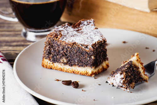 sweets and desserts  pastries  delicious chocolate cake with poppy seeds  raisins and powdered sugar with a cup of black coffee on a dark wooden background