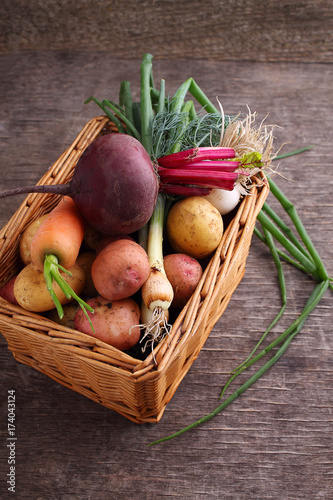 Vegetables in a basket: beets, onions, garlic, dill, potatoes, carrots on an old wooden background